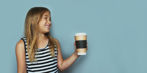 Smiling girl giving, showing coffeecup closeup side view. Drinking hot, energizing coffee to go,...