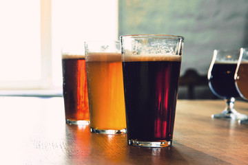 Glasses of different kinds of dark and light beer on wooden table in line. Cold delicious drinks are prepared for a big friend's party. Concept of drinks, fun, meeting, oktoberfest.