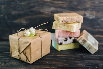 colorful handmade soaps and gift box on dark wooden background