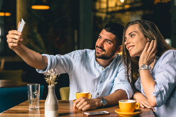 A man taking a picture with his girlfriend at a restaurant