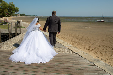 Plakat wedding couple near the ocean walk on path wood