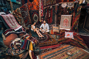 Couple travels the world. Happy couple in the store. Couple in love in Turkey. Man and woman in the Eastern country. Gift shop. Persian shop. Tourists in store. Oriental carpet. Istanbul. Cappadocia