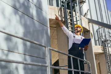 worker controlling grain loading standing by grain silos © cherryandbees