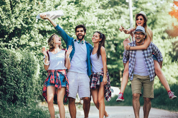 Group of smiling friends walking with backpacks in woods - adventure, travel, tourism, hike and people concept