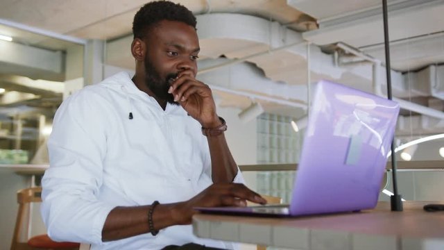 Happy handsome young african american man working use computer looking in monitor screen office technology businessman casual communication successful person portrait smart business slow motion