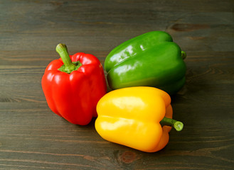 Vibrant Tricolor Bell Peppers Isolated on Dark Brown Wooden Table