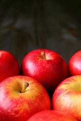 Vertical image of heap of fresh ripe red apples isolated on dark color wooden table with copy space