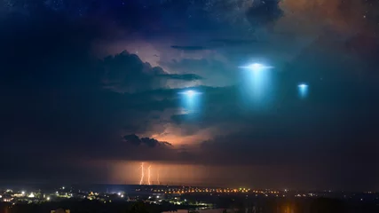 Selbstklebende Fototapete UFO Außerirdische außerirdische Raumschiffe fliegen über der kleinen Stadt, Ufo mit blauen Scheinwerfern in dunklem Gewitterhimmel.