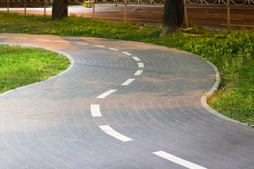 Obraz premium Tiled bike path. Curving sidewalk. Winding road.