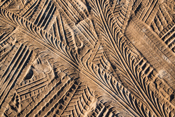 Close up on multiple tire tracks texture detail on beach sand