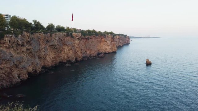 View of bay in Antalya with swallows and plane in the air. Panning mediterranean sea from the cliffs.