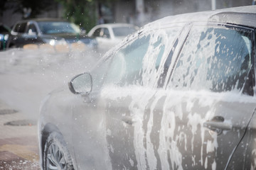 Cleaning car using high pressure water outdoors.