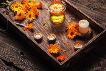Medicinal flowers of calendula with burning candles  on dark wooden background