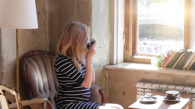 A pregnant blond woman in a cafe drinking tea by the window, sitting on the armchair. beautiful diffused light. Image of an amazing healthy pregnant woman indoors at home sitting posing drinking tea
