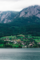 Obraz premium Calm cloudy day on lakefront of Attersee with mountains in background in late summer. lake Attersee in the Austrian Salzkammergut
