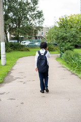 Fototapeta na wymiar Handsome asian boy in glasses going to school. Cute schoolboy with backpack coming back home after school. students