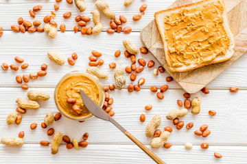 Make sandwiches with peanut butter in glass bowl on white wooden background top view pattern