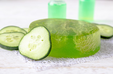 Green cucumber soap on a white background with cucumber slices and cucumber tincture extract in a bottle. Spa treatments with cucumber soap.
