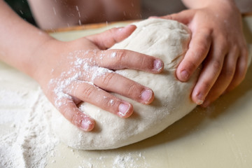 Closeup portrait of kid hands making dough for pastry 