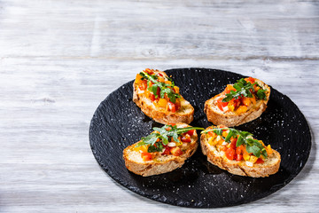 Bruschettas on black stone plate on wooden background