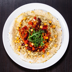 Groats with sauce and vegetables on tortilla