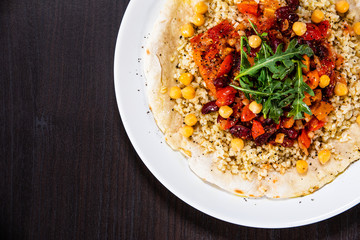 Groats with sauce and vegetables on tortilla