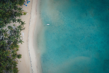Drone shot of tropical beach with white boat anchored.Samana peninsula,Grand Bahia Principe El Portillo beach,Dominican Republic.