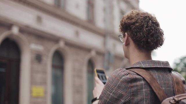 Hipster guy with glasses taking photo on his camera phone travelling in Europe. Tourist man taking picture with camera phone outside.