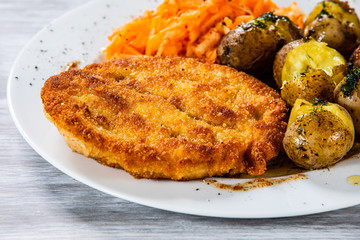 Fried pork chop, boiled potatoes and vegetable salad