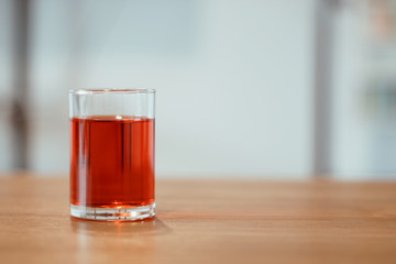 A glass of sweet red soda on the table.