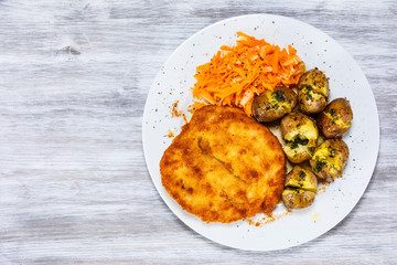 Fried pork chop, boiled potatoes and vegetable salad