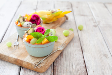 Bowl of healthy fruit tropical salad on wooden background