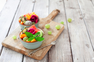 Bowl of healthy fruit tropical salad on wooden background