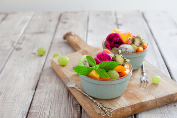 Bowl of healthy fruit tropical salad on wooden background