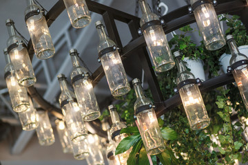 Chandelier with luminous bottle-shaped bulbs and plants