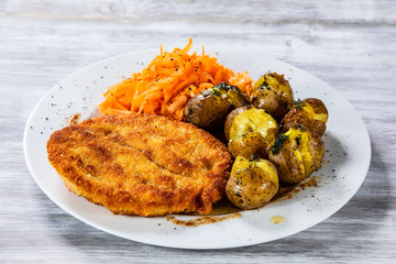 Fried pork chop, boiled potatoes and vegetable salad