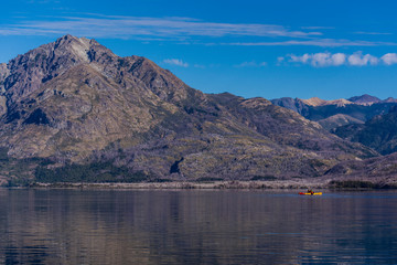 Scene view of a person practicing kayaking at Epuyen lake against Andes mountains in Puerto Patriada, Patagonia, Argentina