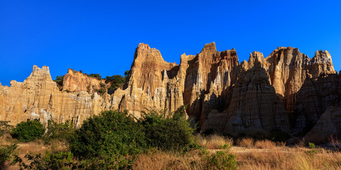 Fototapeta na wymiar Earth Forest of Yuanmou in Yunnan Province, China - Exotic earth and sandstone formations glowing in the sunlight. Naturally formed pillars of rock and clay with unique erosion patterns. China Travel