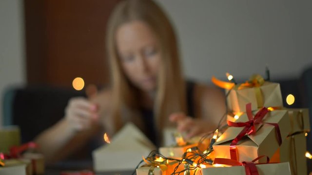 A young woman pack presents. She is tired of making so many presents prior to big holidays. Concept of tiredness from the Christmas and New year