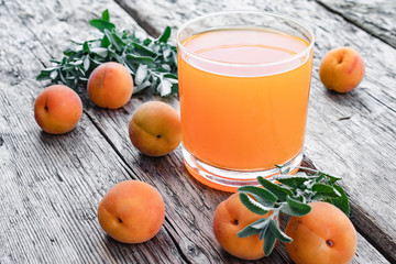 Fresh apricot juice with apricots and twigs of green mint on the background of old boards.