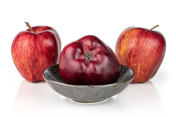 Group of three whole fresh apple red delicious in a dark ceramic bowl isolated on white background