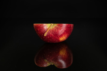 One half of fresh apple red delicious isolated on black glass