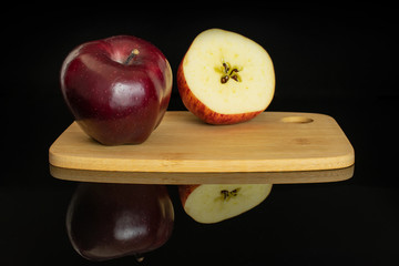 Group of one whole one half of fresh apple red delicious the half is with a star on a bamboo cutting board isolated on black glass