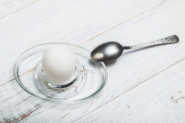 Boiled soft-boiled chicken egg on a white wooden background.