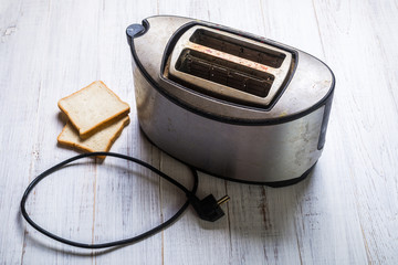 Dirty old toaster with bread on a white wooden background. - Powered by Adobe