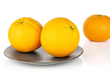 Group of three whole fresh sweet orange one is aside in the back on a gray ceramic plate isolated on white background