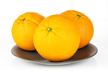 Group of three whole fresh sweet orange on a gray ceramic plate isolated on white background