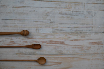 Eco-friendly wooden spoons and honey stick on wooden table background. Environmentally friendly kitchen utensil flat lay with copy space.