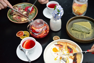 Breakfast table setting with pancakes, tea. Couple is eating