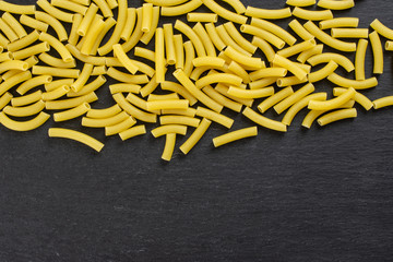 Lot of whole raw pasta macaroni copyspace below flatlay on grey stone